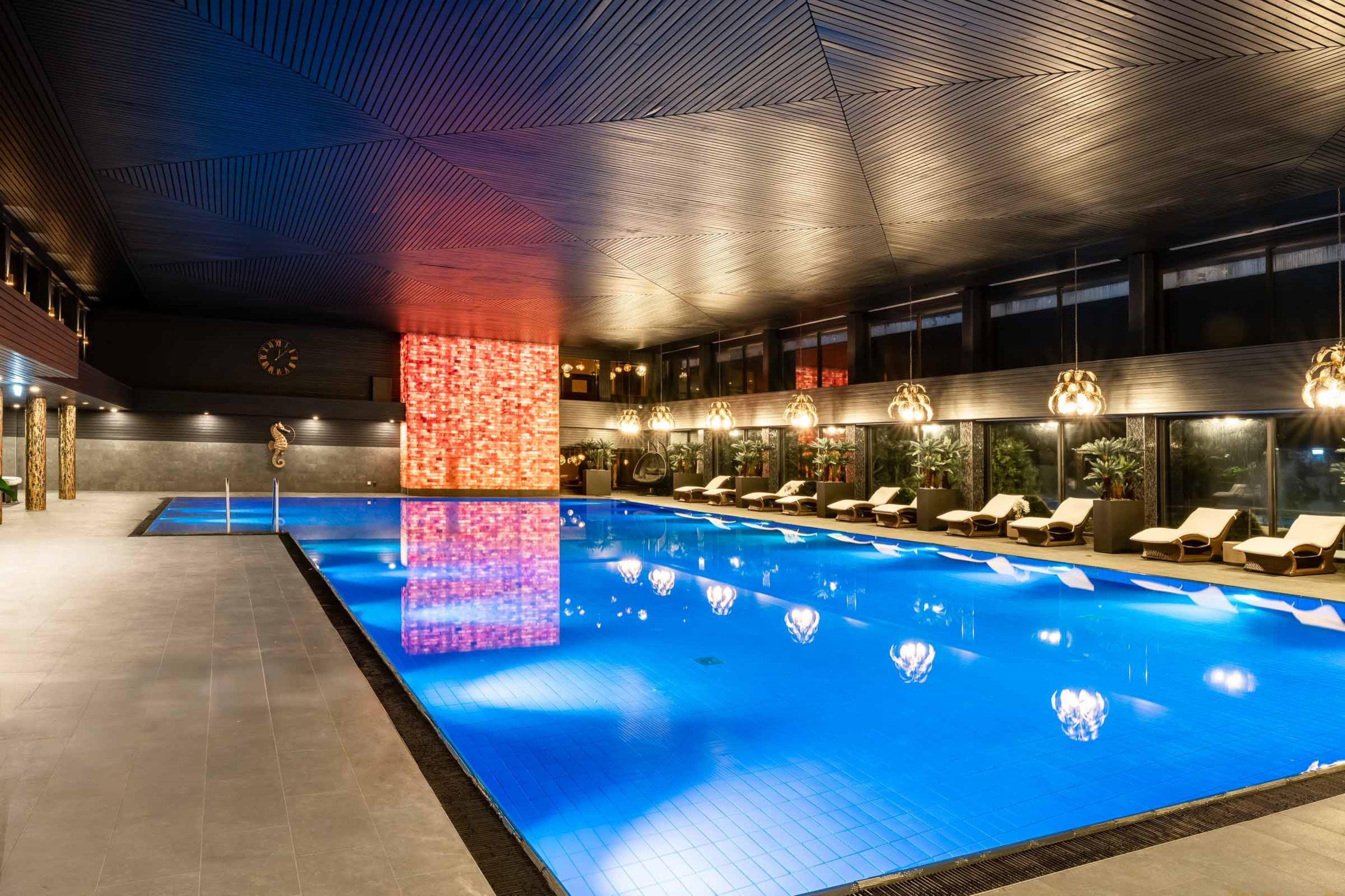 Ein moderner, überdachter Pool mit Liegestühlen und einer Zierwand.