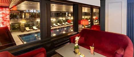 A modern interior with red seating, a pool view, and a bar area.