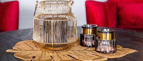 A decorative glass container with handles, two smaller glass containers, and a woven placemat on a table.