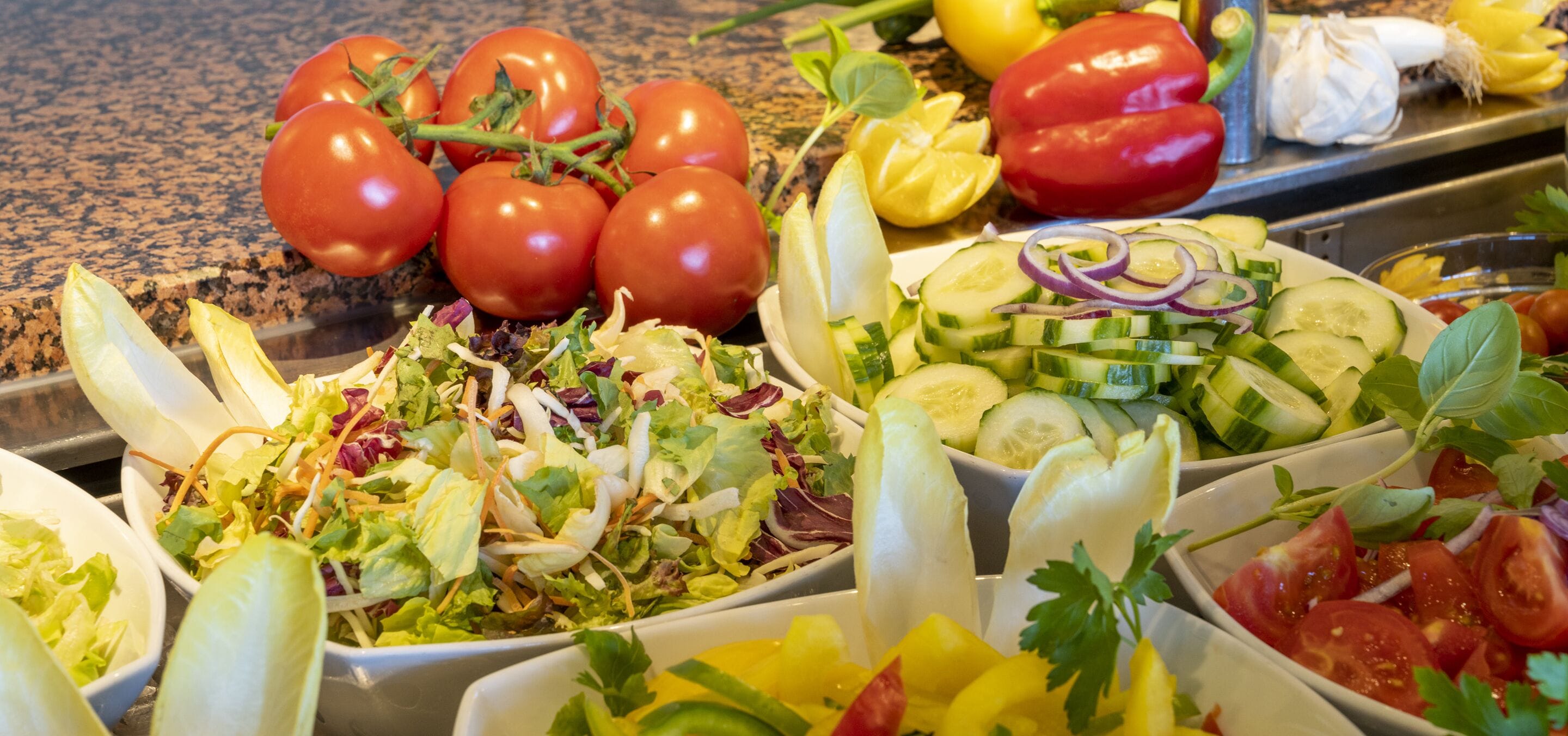 A variety of fresh salads with tomatoes, cucumbers, and other vegetables.