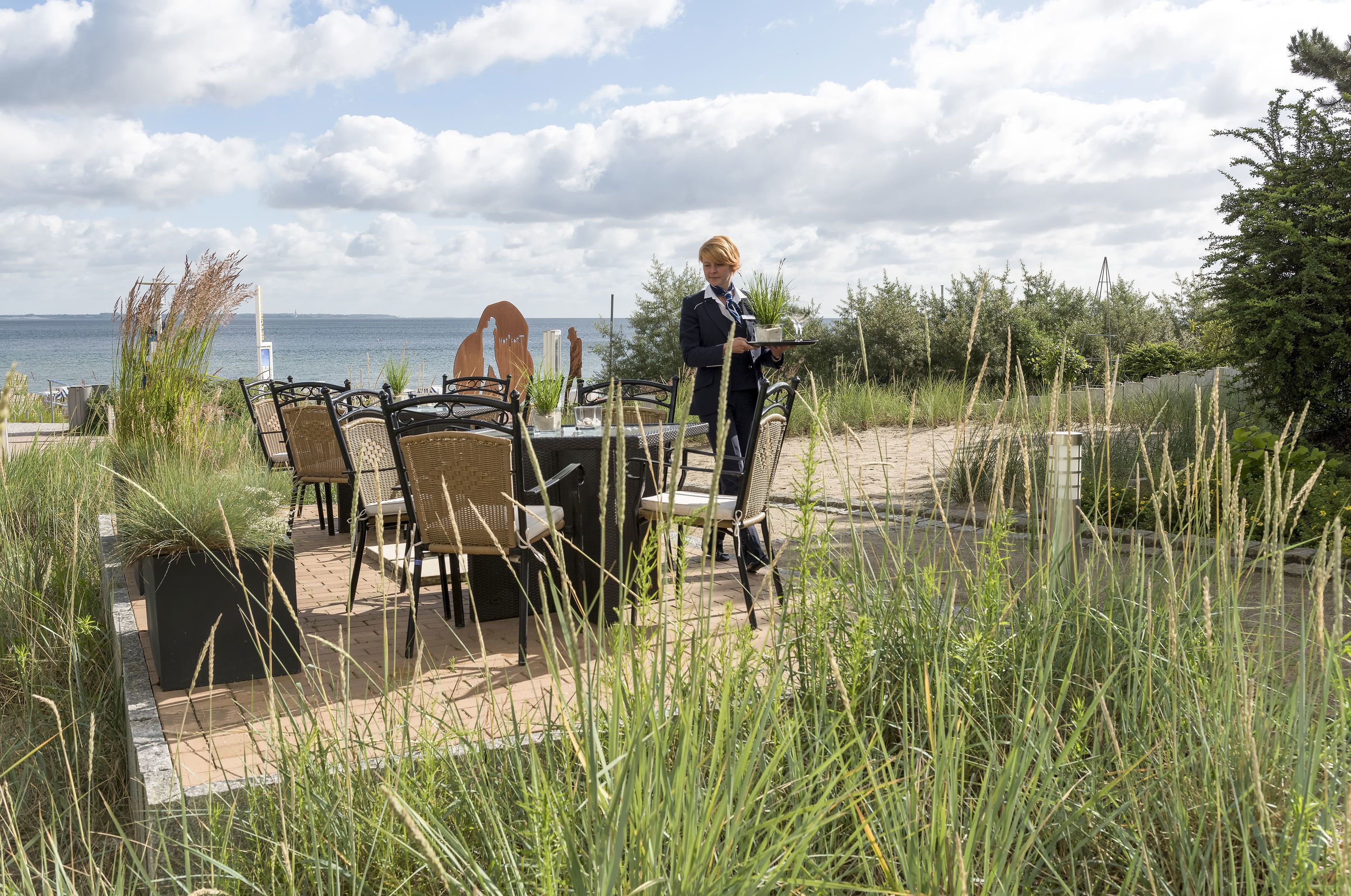 An outdoor seating area with wicker chairs and a table, overlooking a body of water.