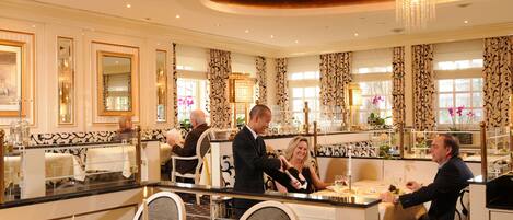 Un comedor elegante con candelabros, espejos ornamentados y cortinas estampadas.
