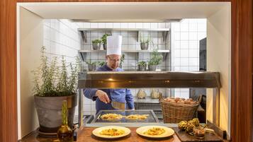 A chef preparing food in a kitchen with a counter, potted plants, and a basket of eggs.