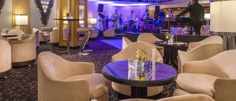 A hotel lobby with plush seating, a stage for live performances, and a bar area.