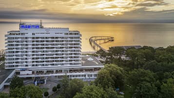 Un hotel moderno con un puerto deportivo y muelle, rodeado de exuberante vegetación.