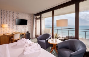 A hotel room with a bed, a desk, a chair, a TV, and a balcony with a view of the sea. - Maritim Seehotel Timmendorfer Strand (Timmendorfer Strand)