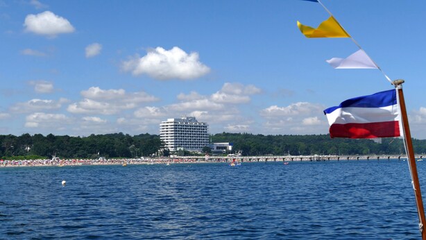 A coastal scene with a hotel, beach, and flags. - Maritim Seehotel Timmendorfer Strand (Timmendorfer Strand)