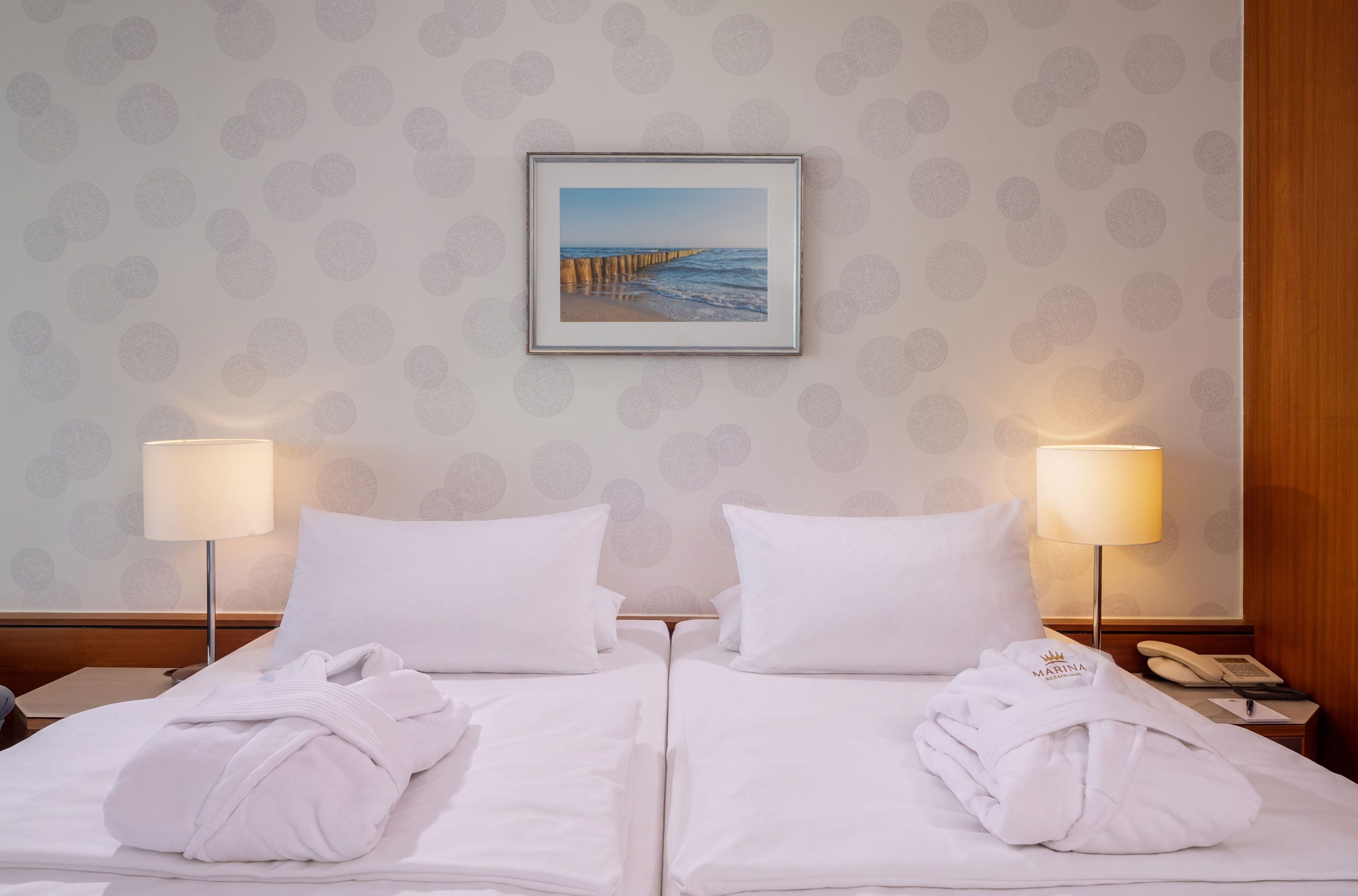 Habitación de hotel con una cama, dos lámparas de noche, un cuadro en la pared y un teléfono en la mesita de noche.