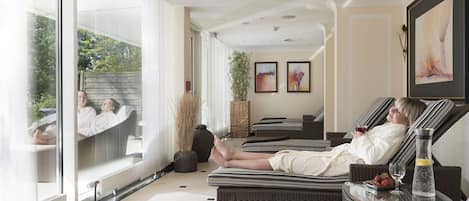 Un espacio de spa con sillones reclinables, un ventanal grande y una pared decorada con obras enmarcadas.