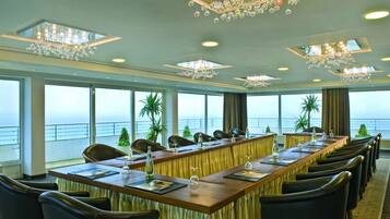 A conference room with a long table, chairs, and a view of the sea.