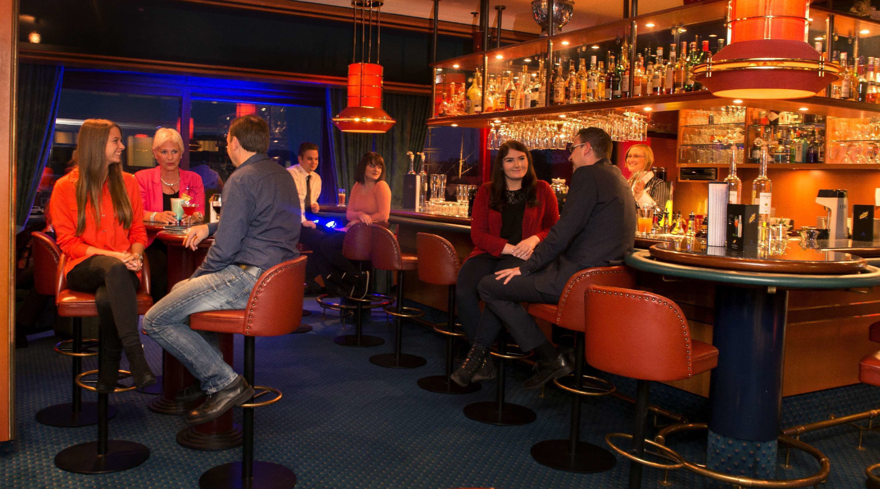 A bar area with multiple stools and a bar counter stocked with bottles.