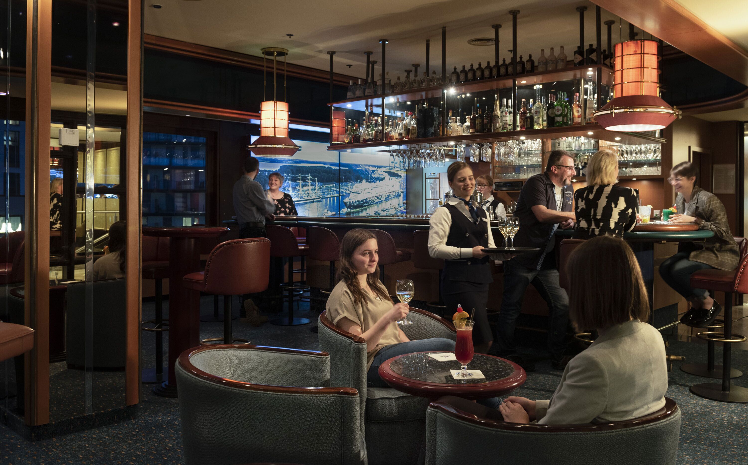 A bar area with seating, a bartender, and a large wine bottle display.