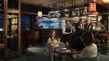 Zona de bar con asientos, un barman y una amplia exhibición de botellas de vino.