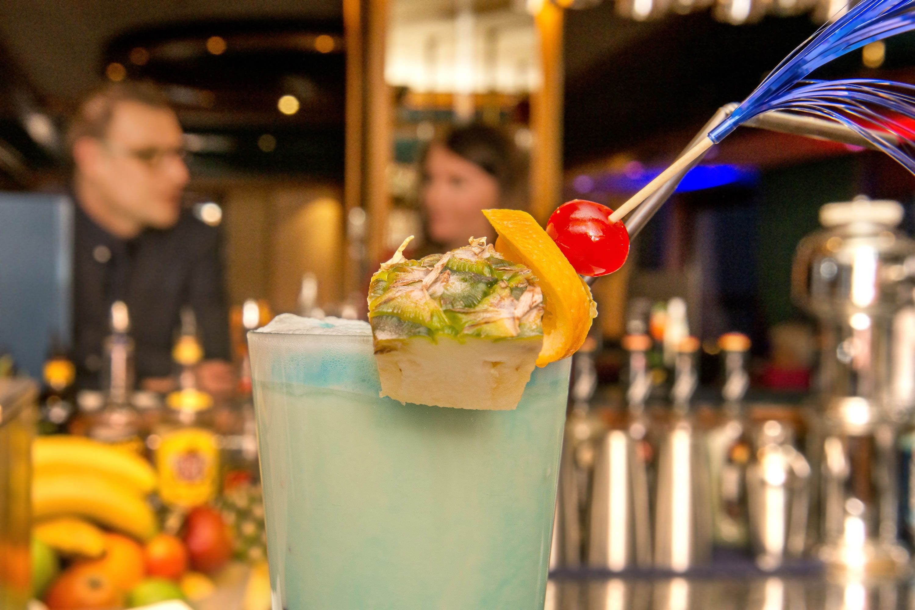 A bar setting with a drink garnished with a cherry and a slice of lemon.