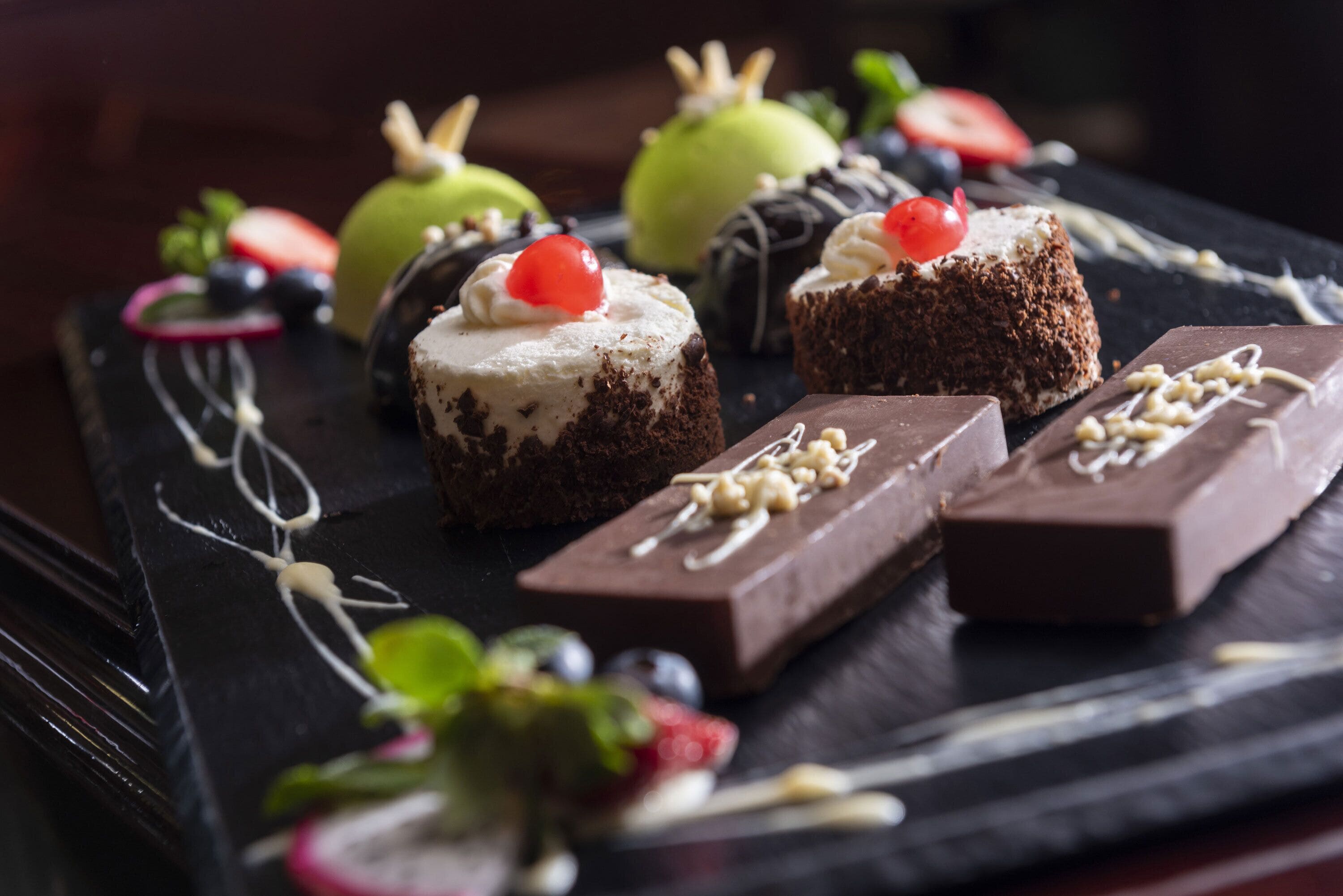 Eine Dessertplatte mit verschiedenen Schokoladen- und Fruchtleckereien auf einer Schieferplatte.