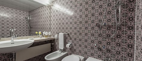 A bathroom with a sink, bidet, toilet, and bathtub.