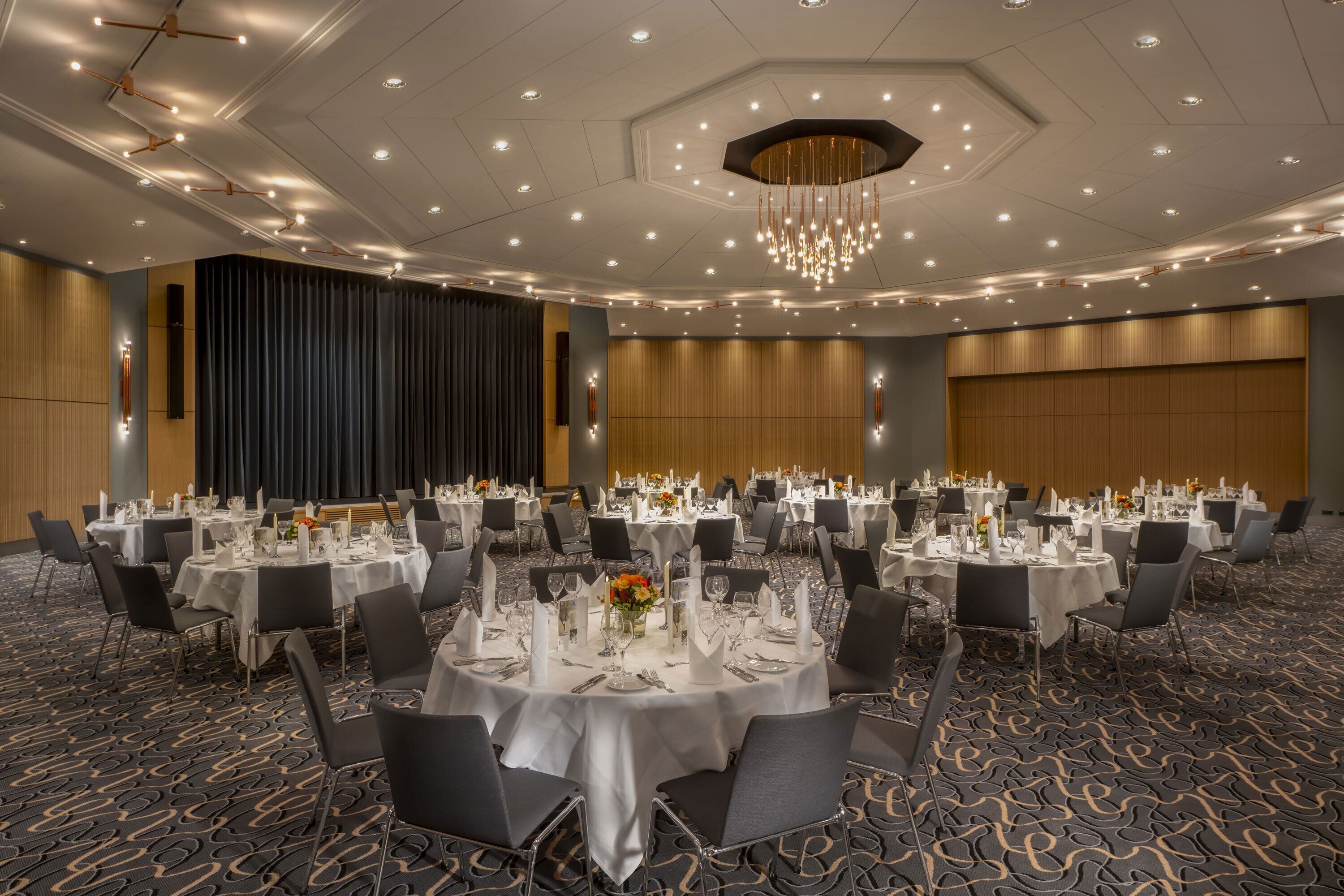 A banquet hall with round tables set for dining, equipped with chairs and table settings.