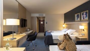 Une chambre d’hôtel avec un lit, un bureau, une chaise et un jouet en peluche en forme de girafe.