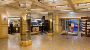 A hotel lobby with a reception desk, a glass door entrance, and a display of brochures. - Maritim Hotel Würzburg (Würzburg)