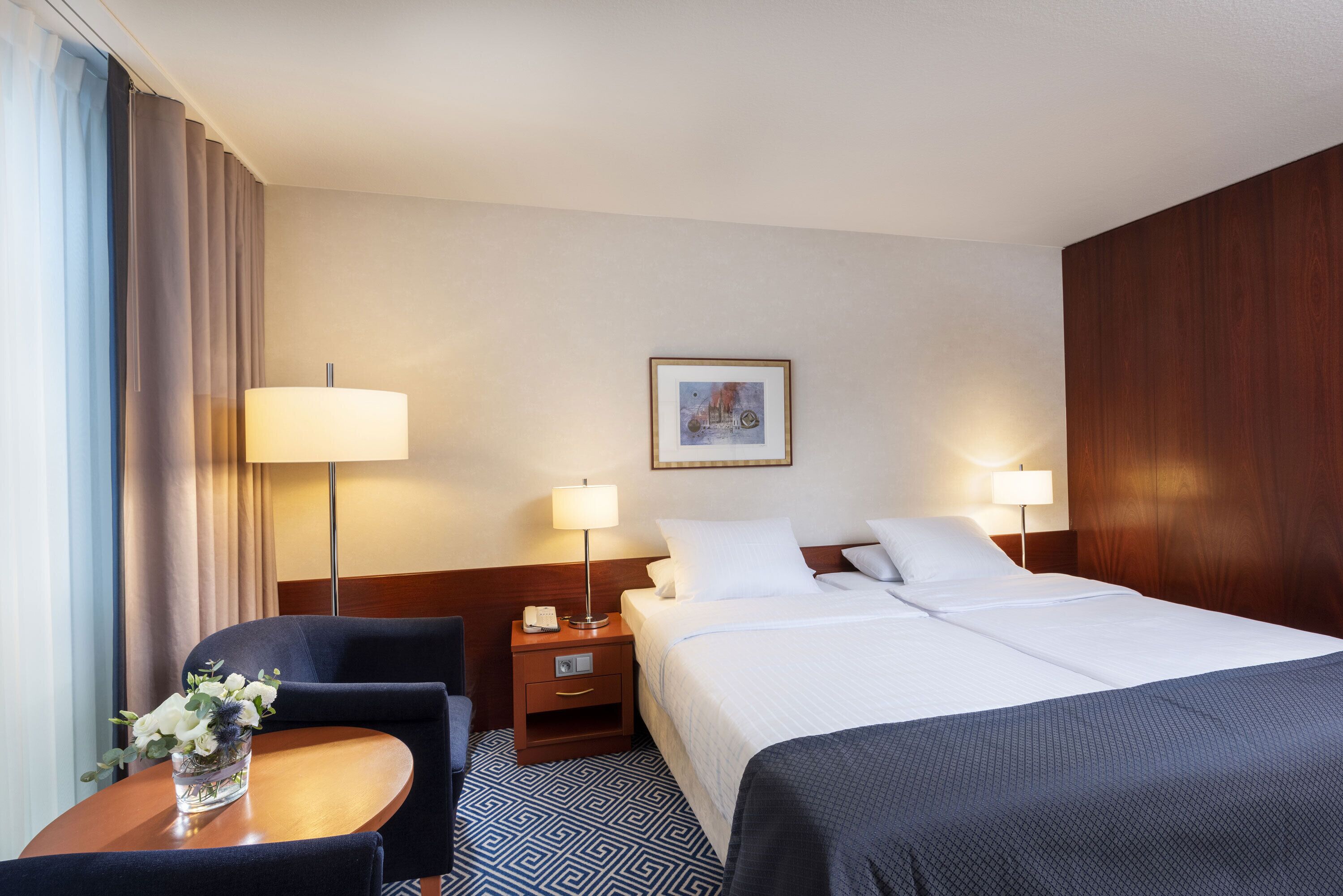 Una habitación de hotel con cama, mesitas de noche, escritorio, silla y lámpara.