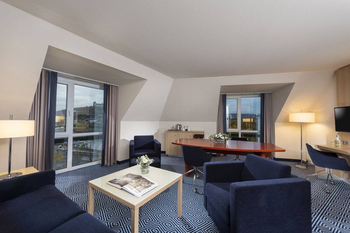 Ein Hotelzimmer mit Essbereich, einer Couch, einem Couchtisch und einem Fernseher.