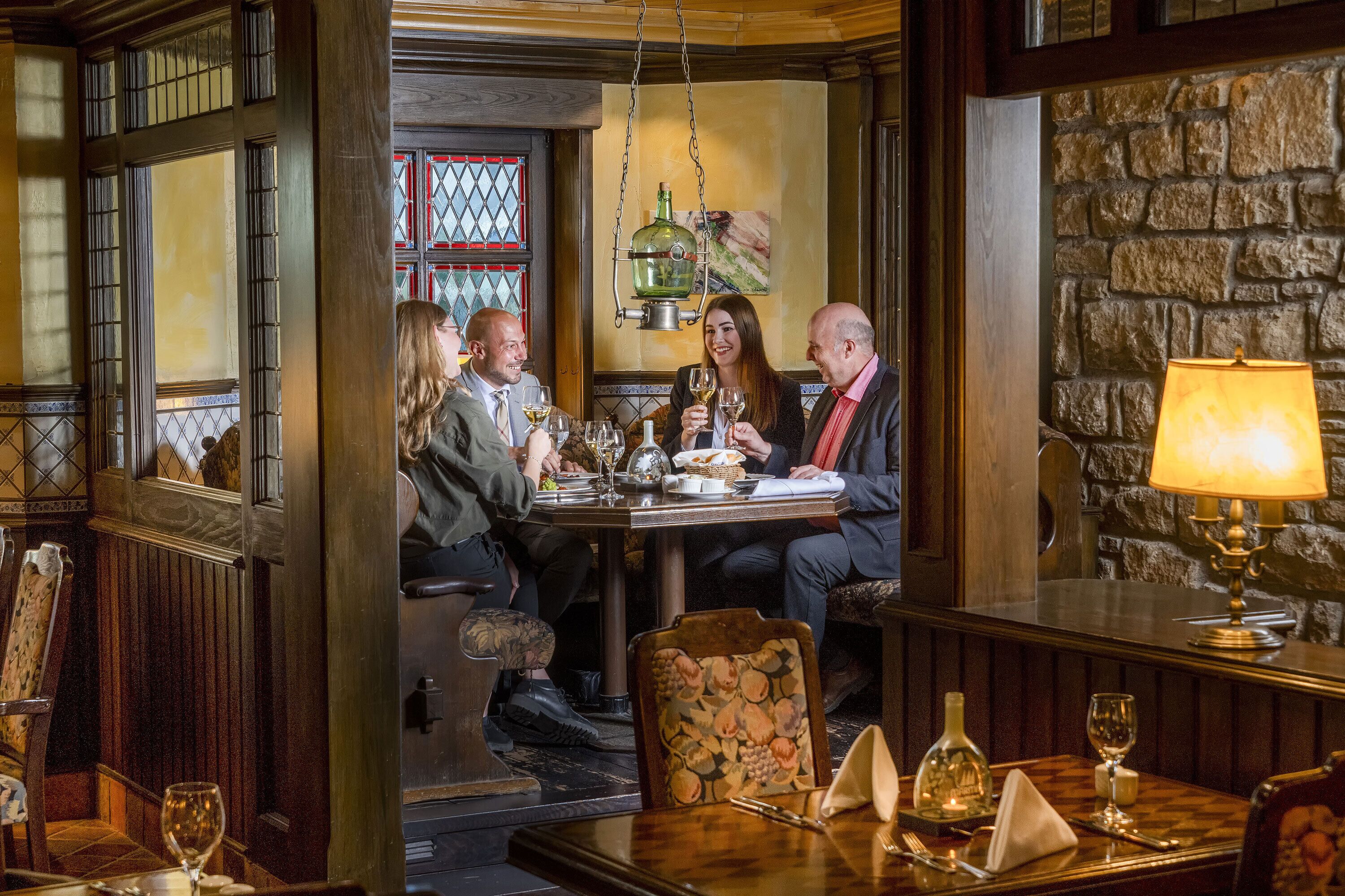 A dining area with a stone wall, wooden furniture, and a hanging light fixture.