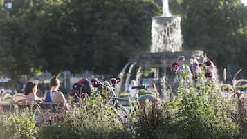 A park with a fountain, benches, and people sitting.