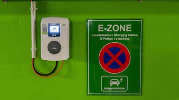 Una estación de carga para vehículos eléctricos con un letrero que indica que es una estación de carga E-ZONE.