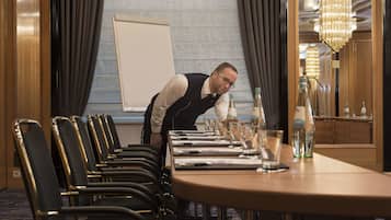 Ein Konferenzraum mit langem Tisch, Stühlen und einer Whiteboard-Tafel.