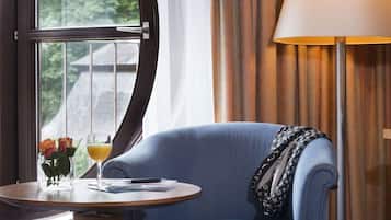 A room with a blue armchair, a small round table with a glass of orange juice, a pen, and a notebook.
