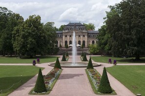 A grand building with a central fountain, surrounded by well-manicured gardens and symmetrical pathways.