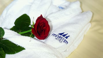 Toalla blanca con una rosa roja y un logotipo.