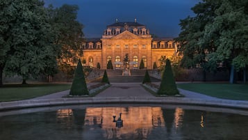 A grand building with a symmetrical facade, a central staircase, and a reflective water feature in the foreground.