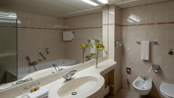 Ein Badezimmer mit einem großen Waschbecken, Spiegel, Bidet und einem Handtuchhalter.