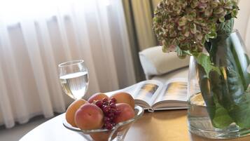Uma mesa com uma tigela de frutas, um copo de água e um vaso com flores.