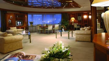 A spacious hotel lobby with a high ceiling, a television, a dining area, and comfortable seating.