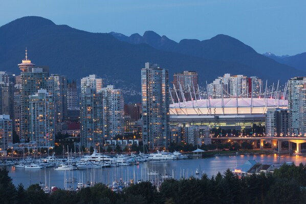Une vue urbaine comprenant un stade imposant, des immeubles de grande hauteur et un port de plaisance avec des bateaux.