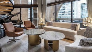 A modern living room with a piano, two sofas, and round tables. - Metropolitan Hotel Vancouver by Marriott (Vancouver)