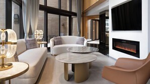 A modern living room with a sofa, two round tables, a leather armchair, a fireplace, and a large window with curtains. - Metropolitan Hotel Vancouver by Marriott (Vancouver)