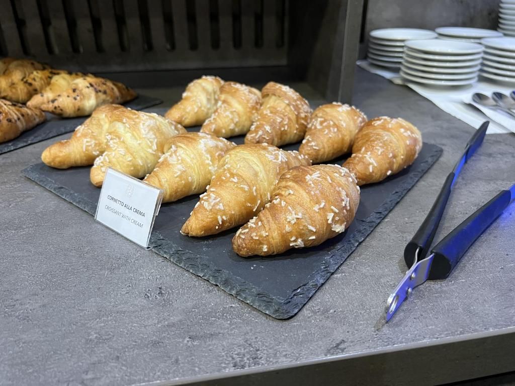 A display of croissants with a sign indicating they are 'cornetto alla crema croissant with cream.'