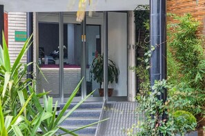 A hotel entrance with a glass door, a staircase leading up, and a potted plant to the right. - Hotel Milano Palmanova (Milan)