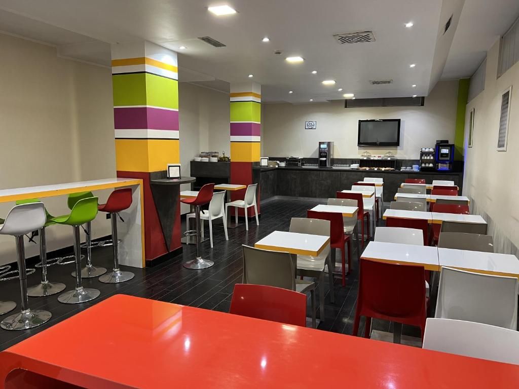A modern cafe with multiple seating areas, including bar stools and tables, and a counter with a coffee machine.