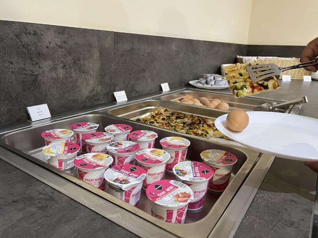 Un bufé con recipientes de yogur, huevos y una persona sirviendo comida.