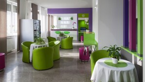 A modern lobby with green and white furniture, a reception desk, and a purple accent wall. - Hotel Milano Palmanova (Milan)