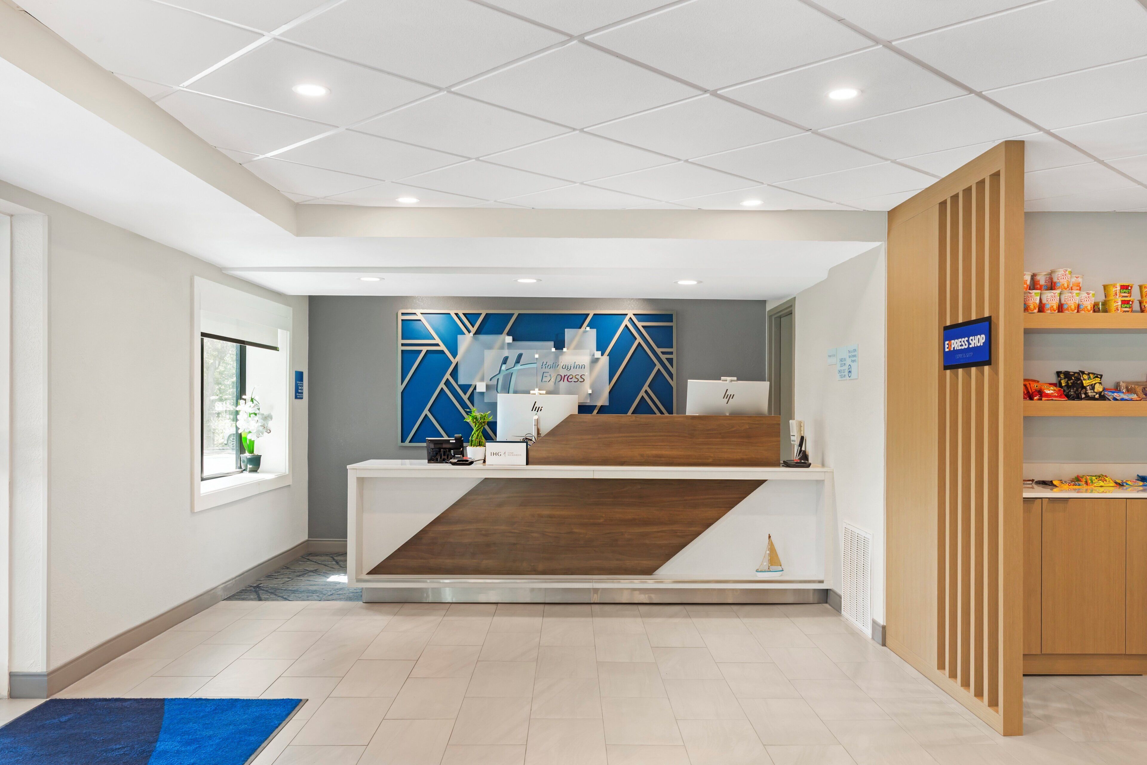 Un espace d’accueil au design moderne, un comptoir d’accueil, un mur aux couleurs bleu et blanc, et une enseigne indiquant un point de vente de journaux et de magazines en ligne.