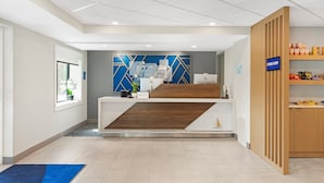 A reception area with a modern design, a reception desk, a blue and white wall, and a sign indicating an E-Press Shop. - Holiday Inn Express Hyannis Cape Cod by IHG (Hyannis)