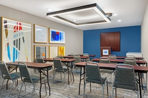 A conference room with tables and chairs, a blue accent wall, and framed artwork.