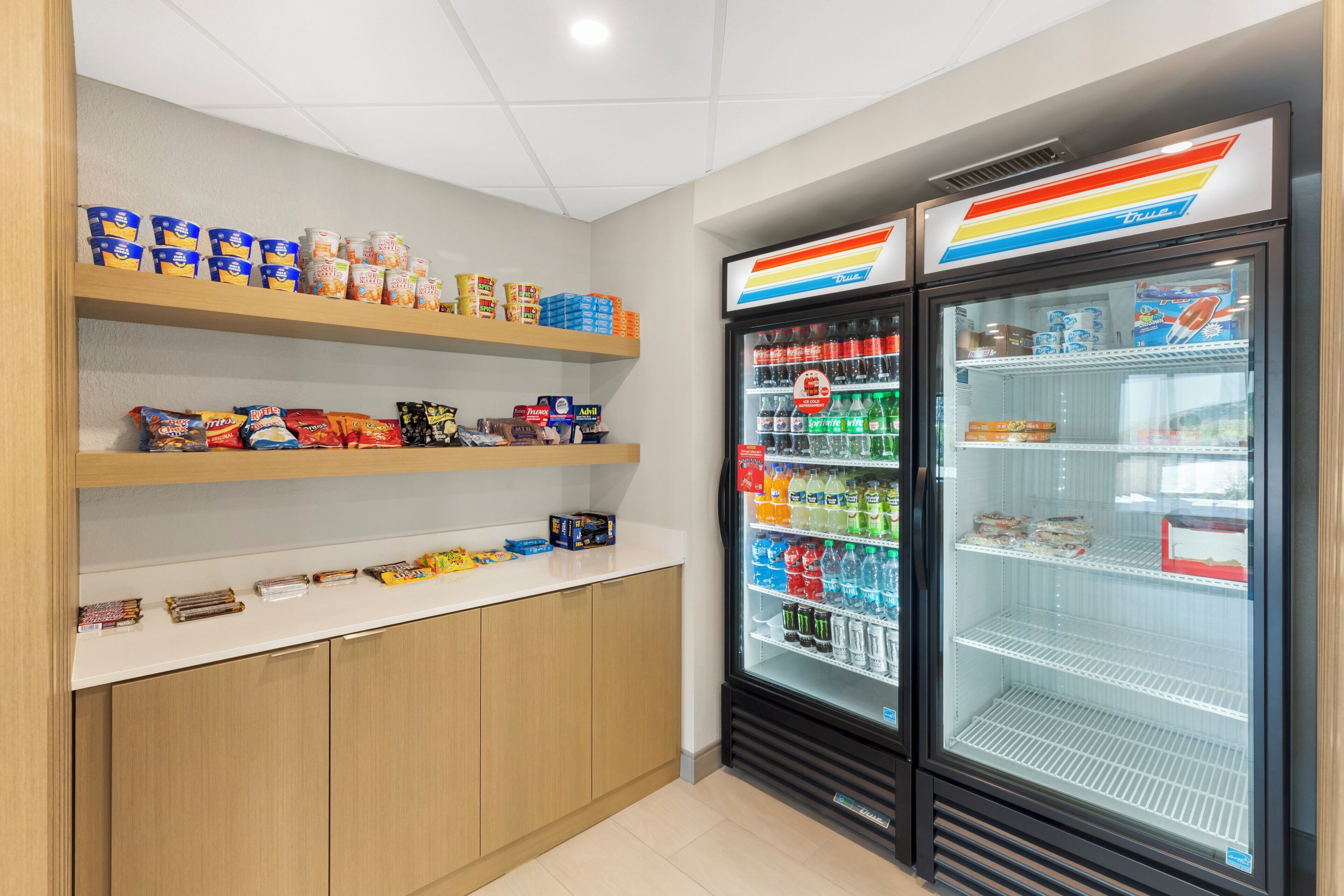 A snack bar with shelves stocked with various snacks and a refrigerated display case with beverages.