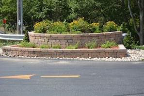 A landscaped garden with a brick retaining wall and yellow flowers. - Holiday Inn Express Hyannis -Cape Cod (Hyannis)