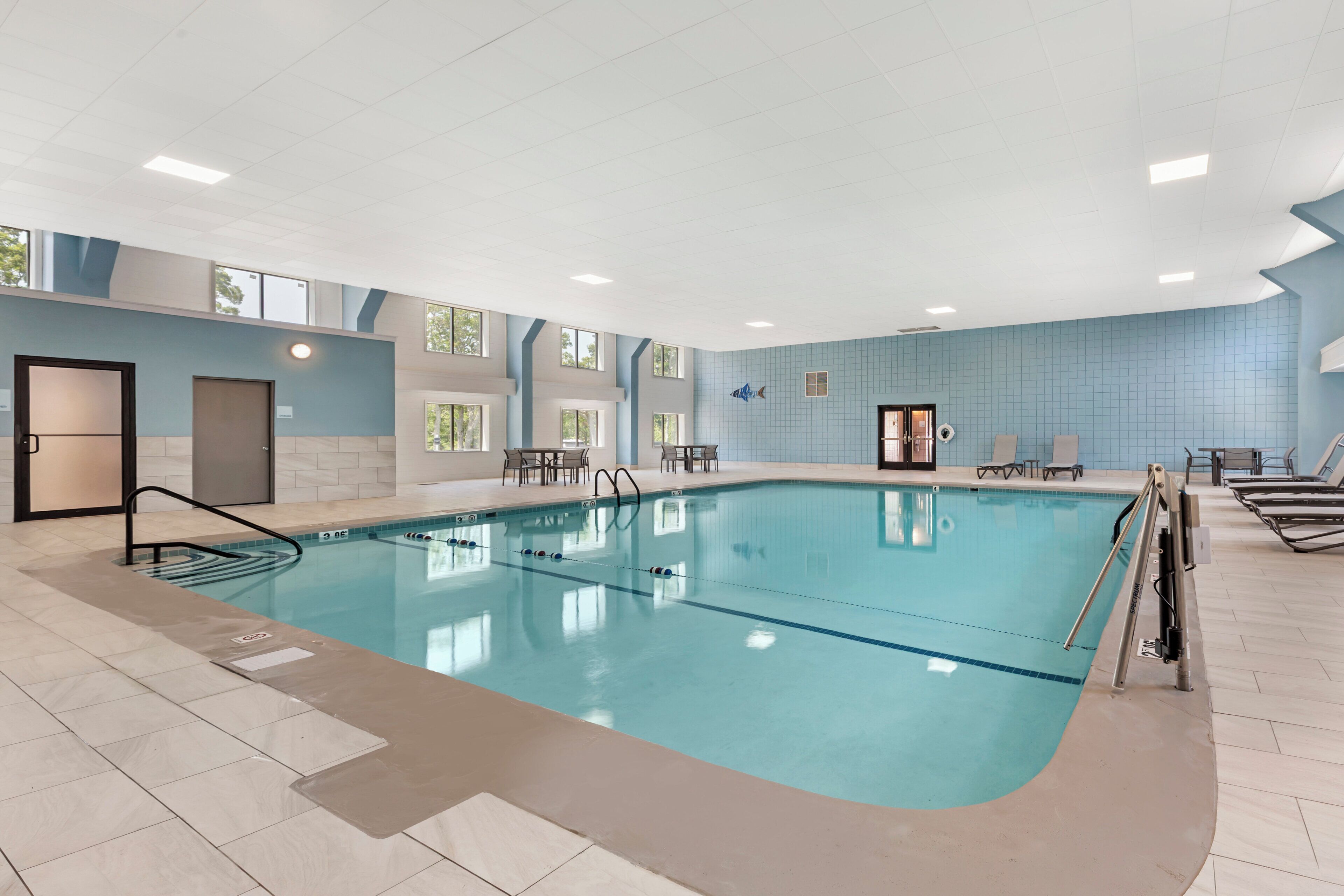 Piscina interior con carriles delimitados, vestuario y zona de estar con sillones.